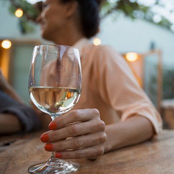 A person holding a glass of white wine