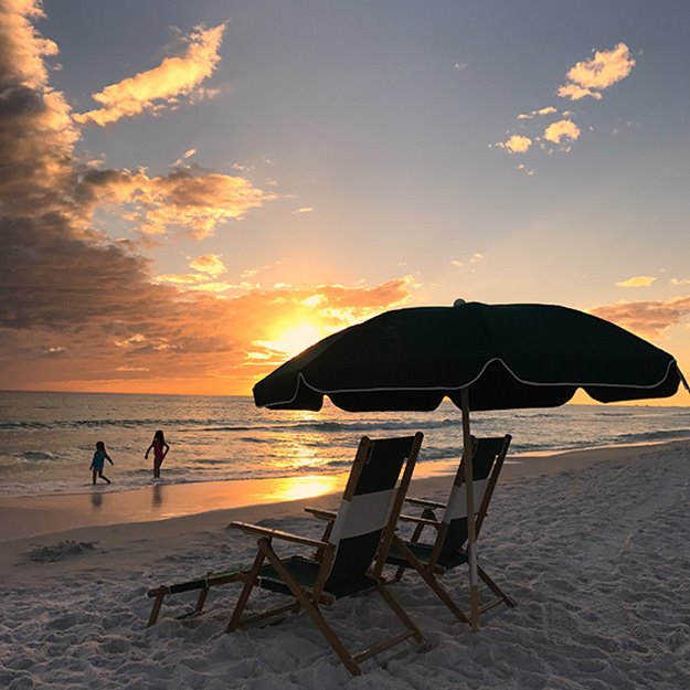A beach chair and umbrella at sunset