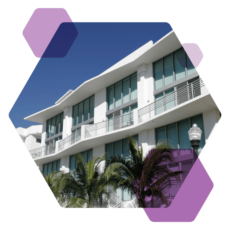 A residential building is showcased, with clear blue skies and palm trees in front.