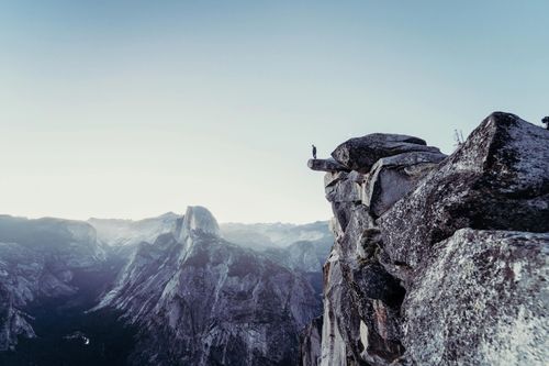Person standing on gray concrete cliff photo
