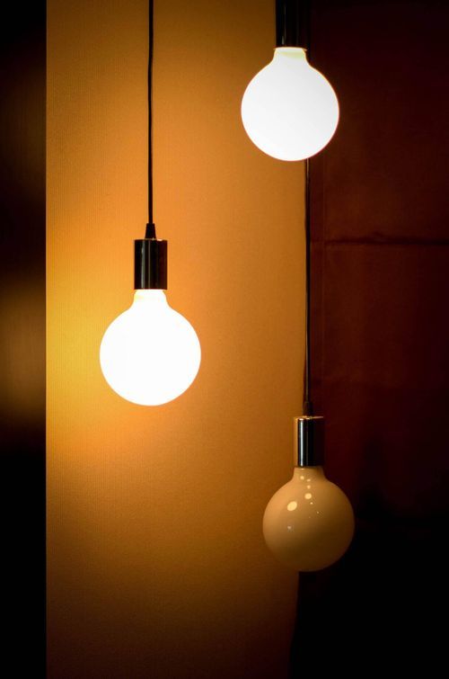 Two lightbulbs tued on with a third one switched off in a dark room. 