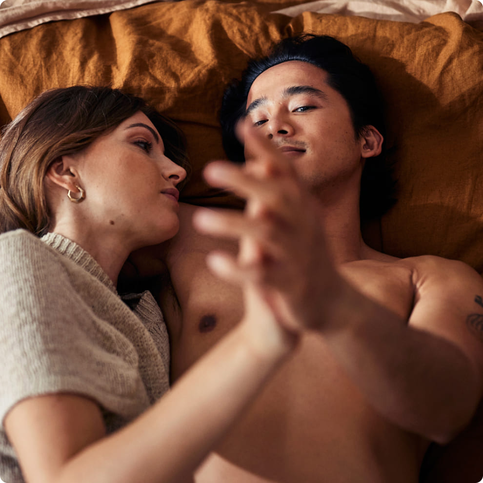 Man and woman hold hands in bed