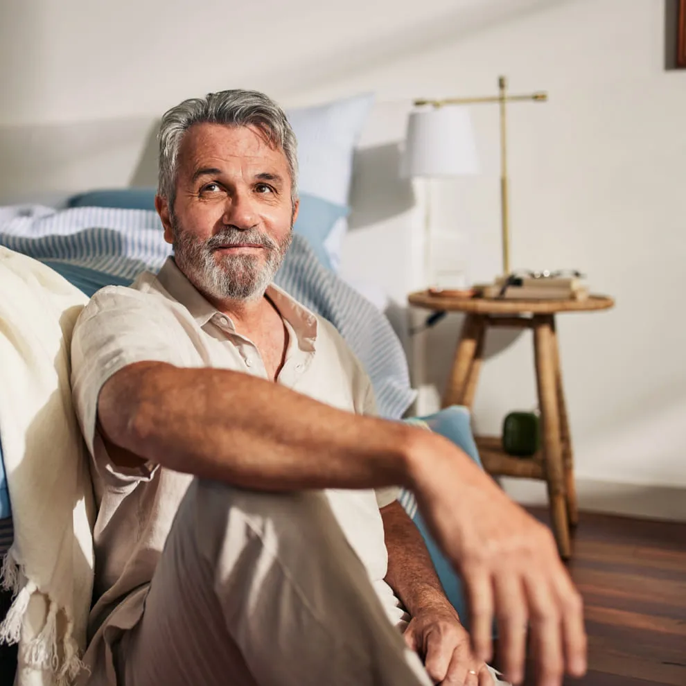 A man sitting next to his bed