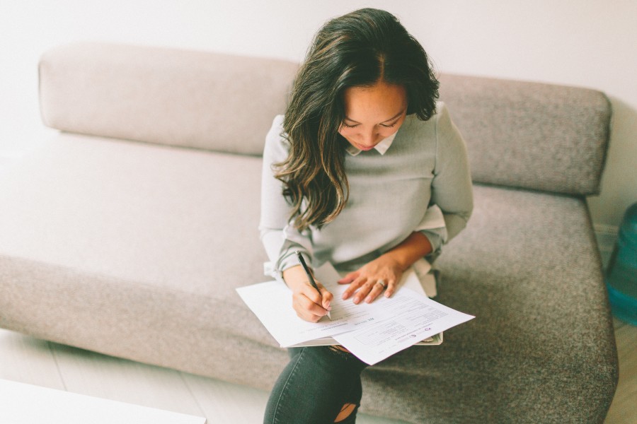 Women Signing A Declaration Form While Sitting On The Couch