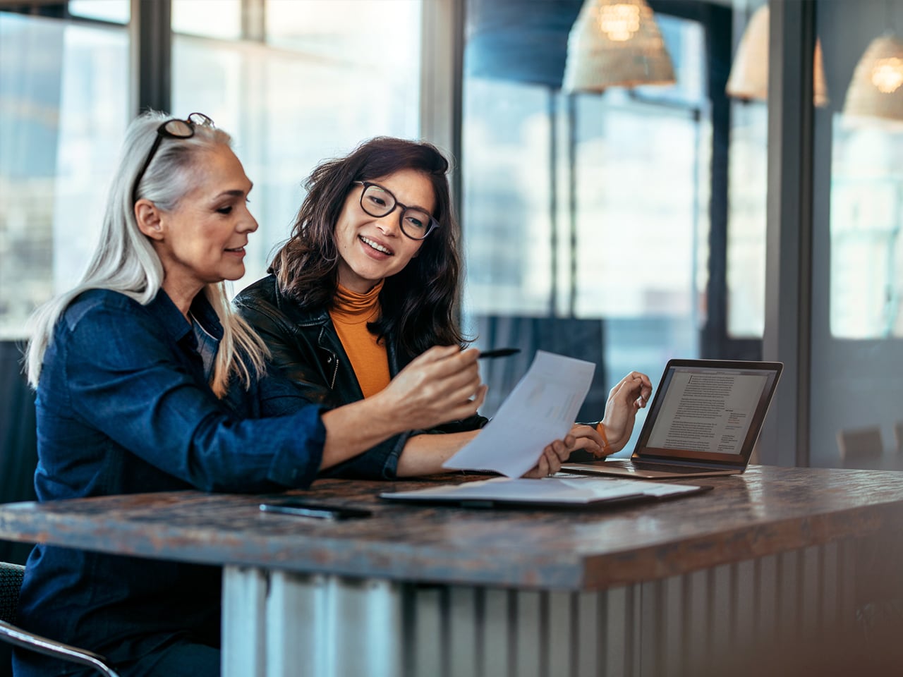 Two women analyzing documents at office and provide purpose an direction with clear objectives