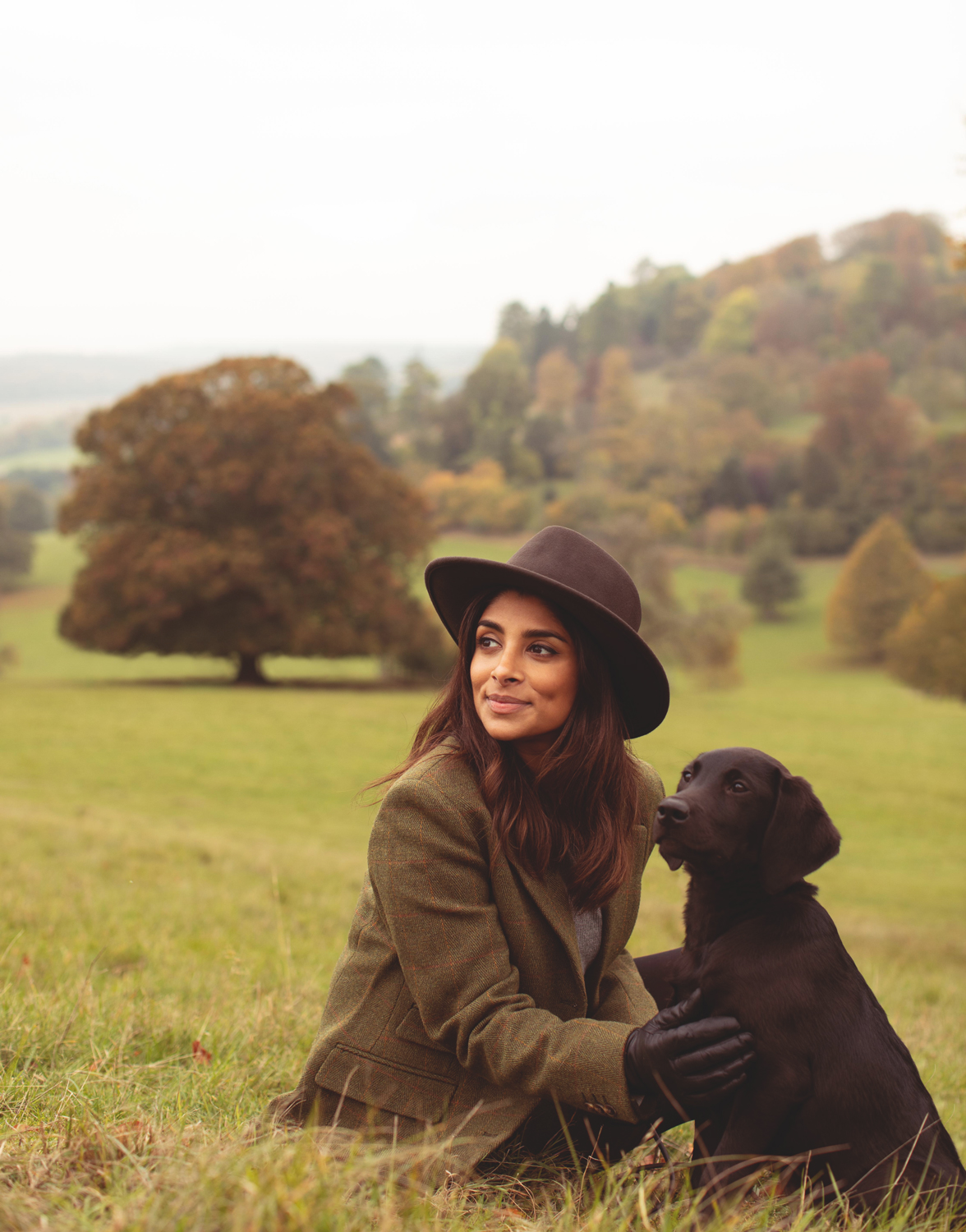 Woman sitting in a field with a puppy