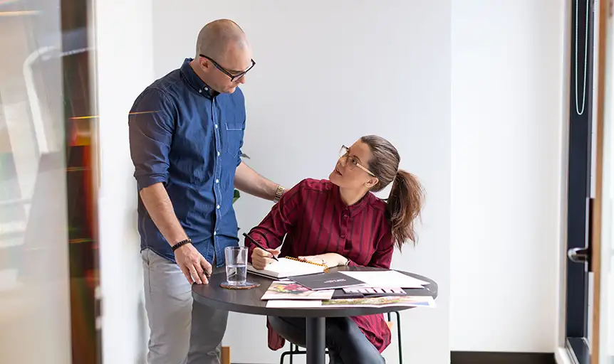 Amanda and Rory chatting and smiling while they talk about graphic design in their Brisbane studio.