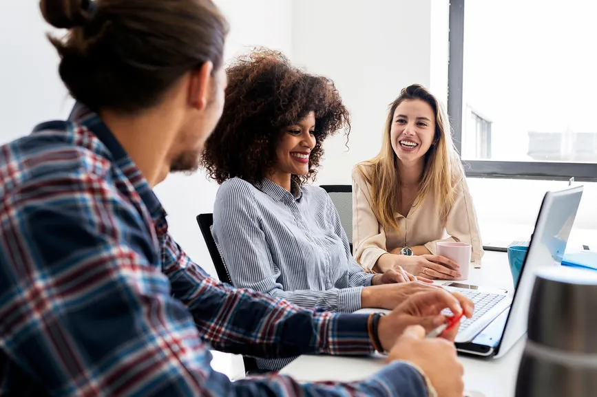 Coworkers smiling and talking while working at a conference table