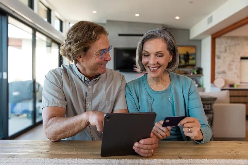 A son showing his mother how to use her tablet to pay