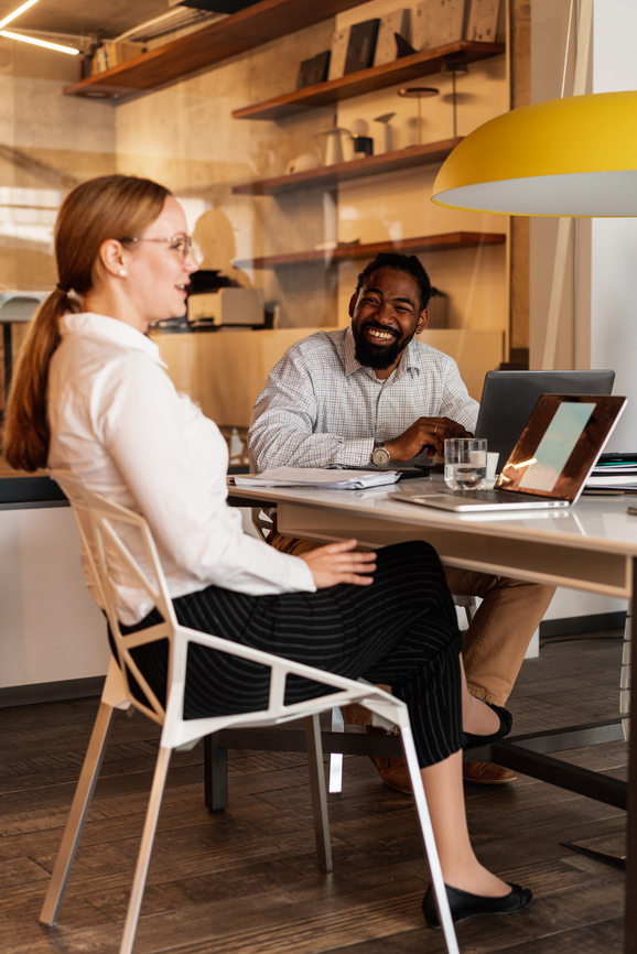 a man and woman sitting at a table with a laptop