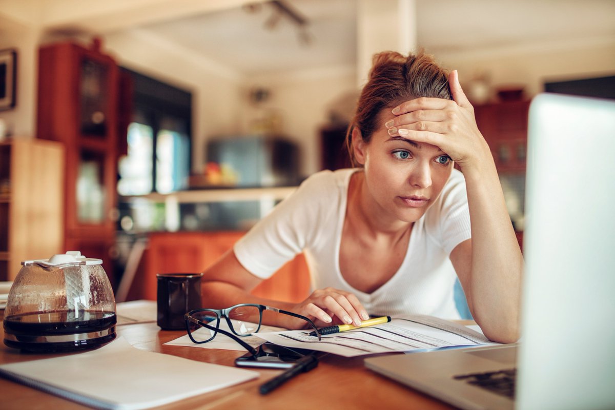 adult woman in stress while looking at her laptop screen and drinking coffee