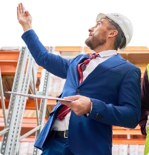 Warehouse manager pointing at storage rack wearing a hard had and suit