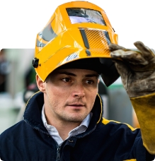 male welder wearing a welding mask smiling at the camera