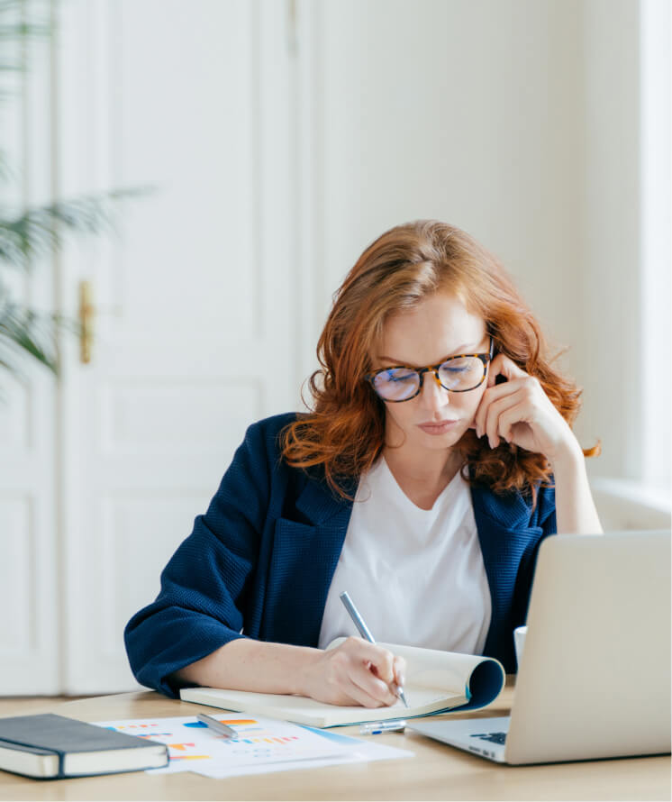 Une expert comptable en train de prendre des notes devant son ordinateur portable