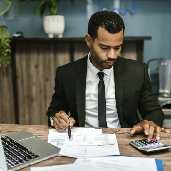 a man sitting at a table writing on a piece of paper