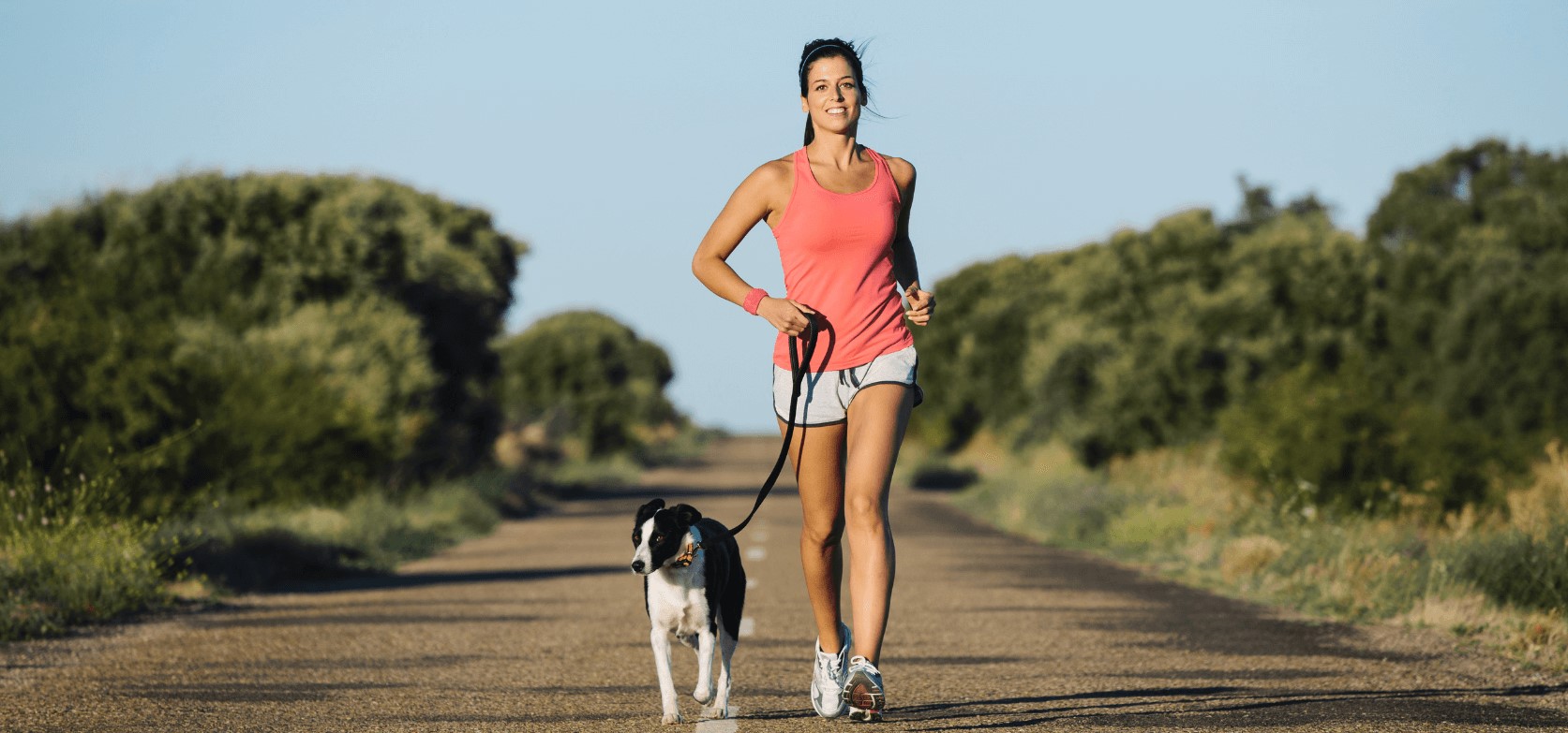 Eine Frau joggt mit ihrem Hund in einem Park.