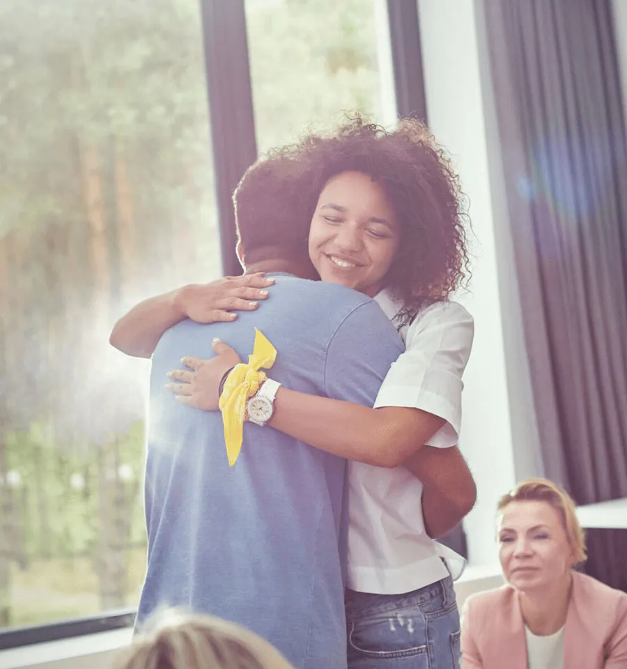 Two people hugging in a room and smiling