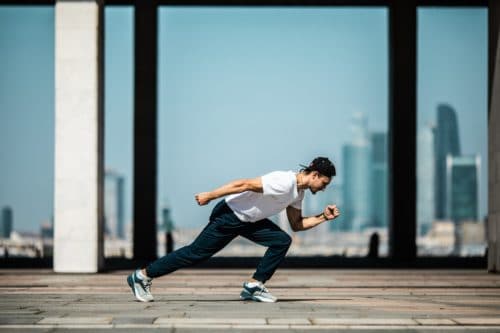 Profile image of a person in running position against a city backdrop.