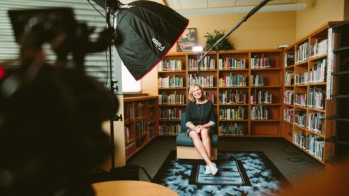 A person being interviewed on camera in front of a bookshelf.