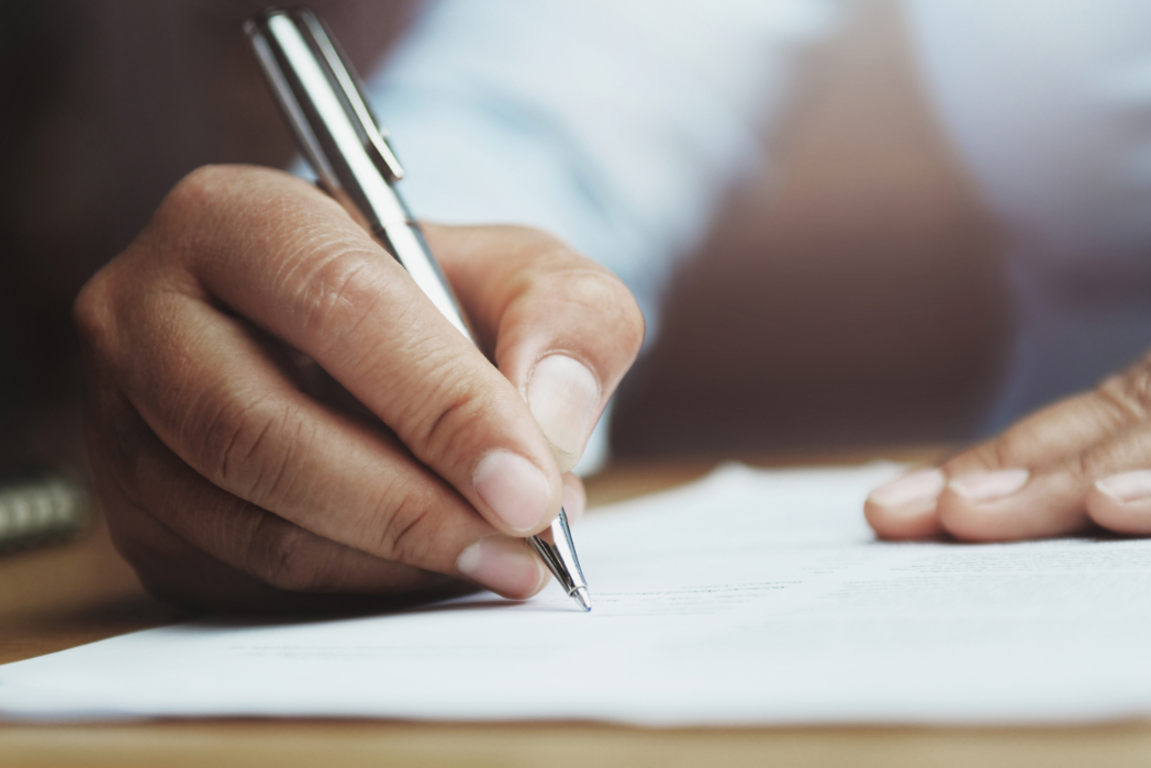 A hand holding a pen writing on paper.