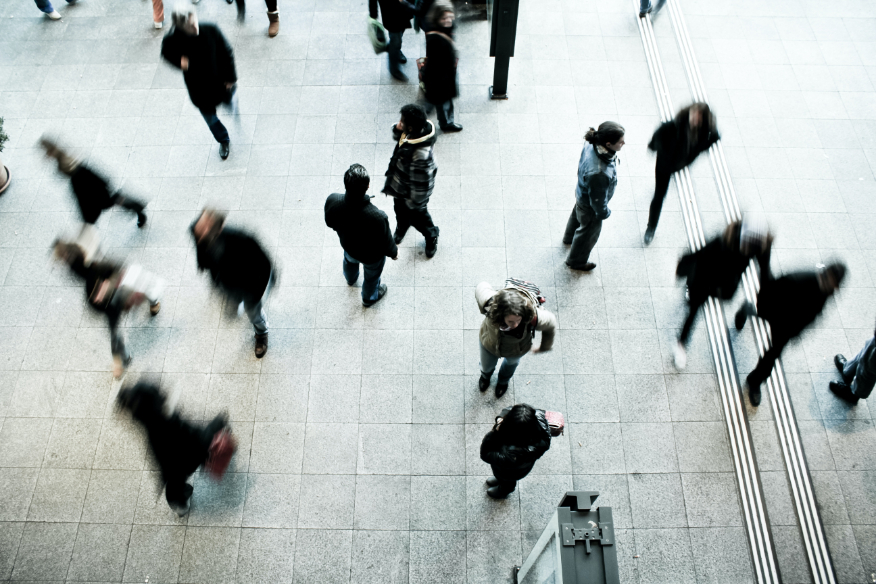 Multiple people walking on a sidewalk.