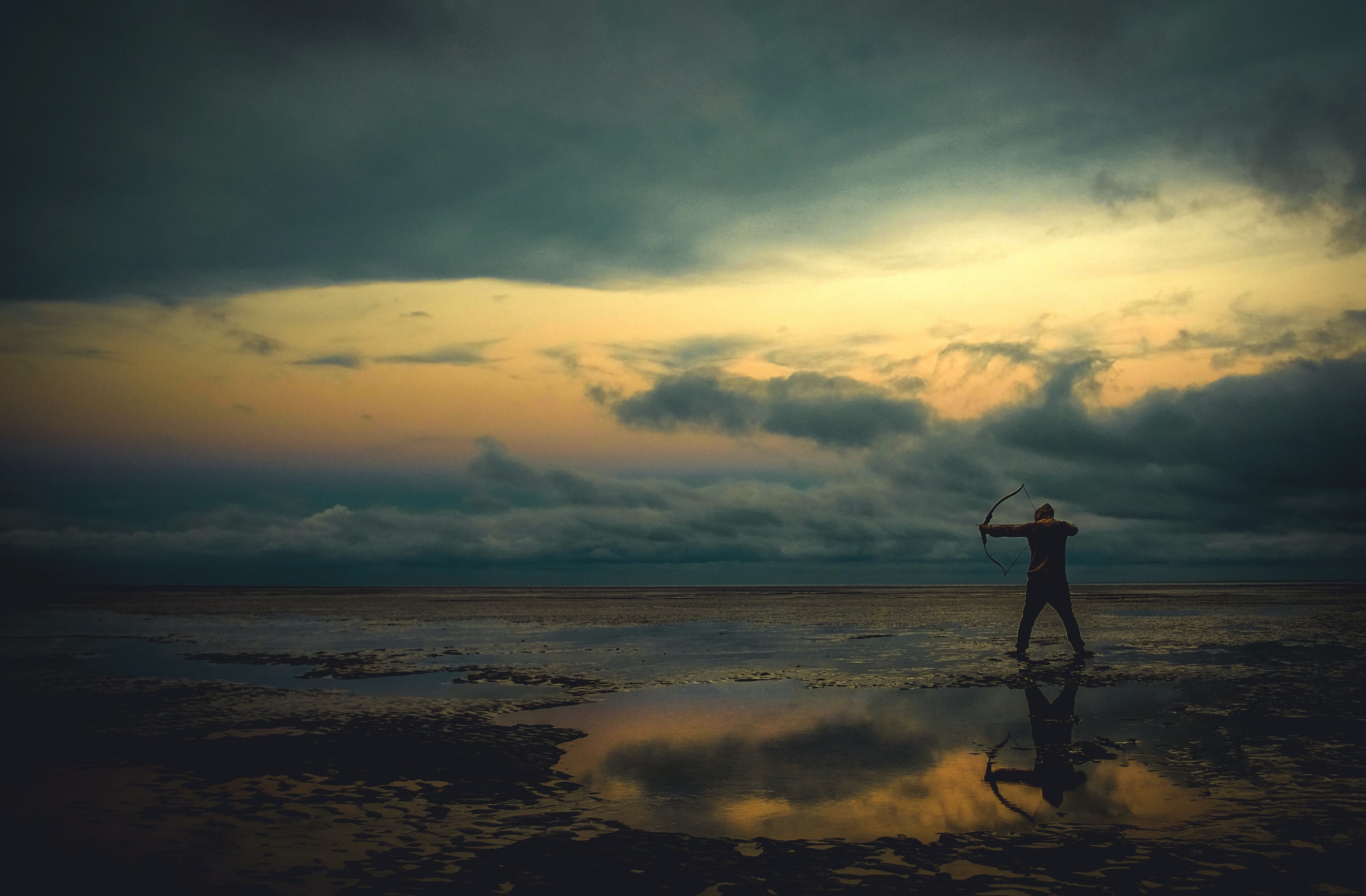 A fantasy character standing on a wet surface under a cloudy sky aims a bow and arrow.