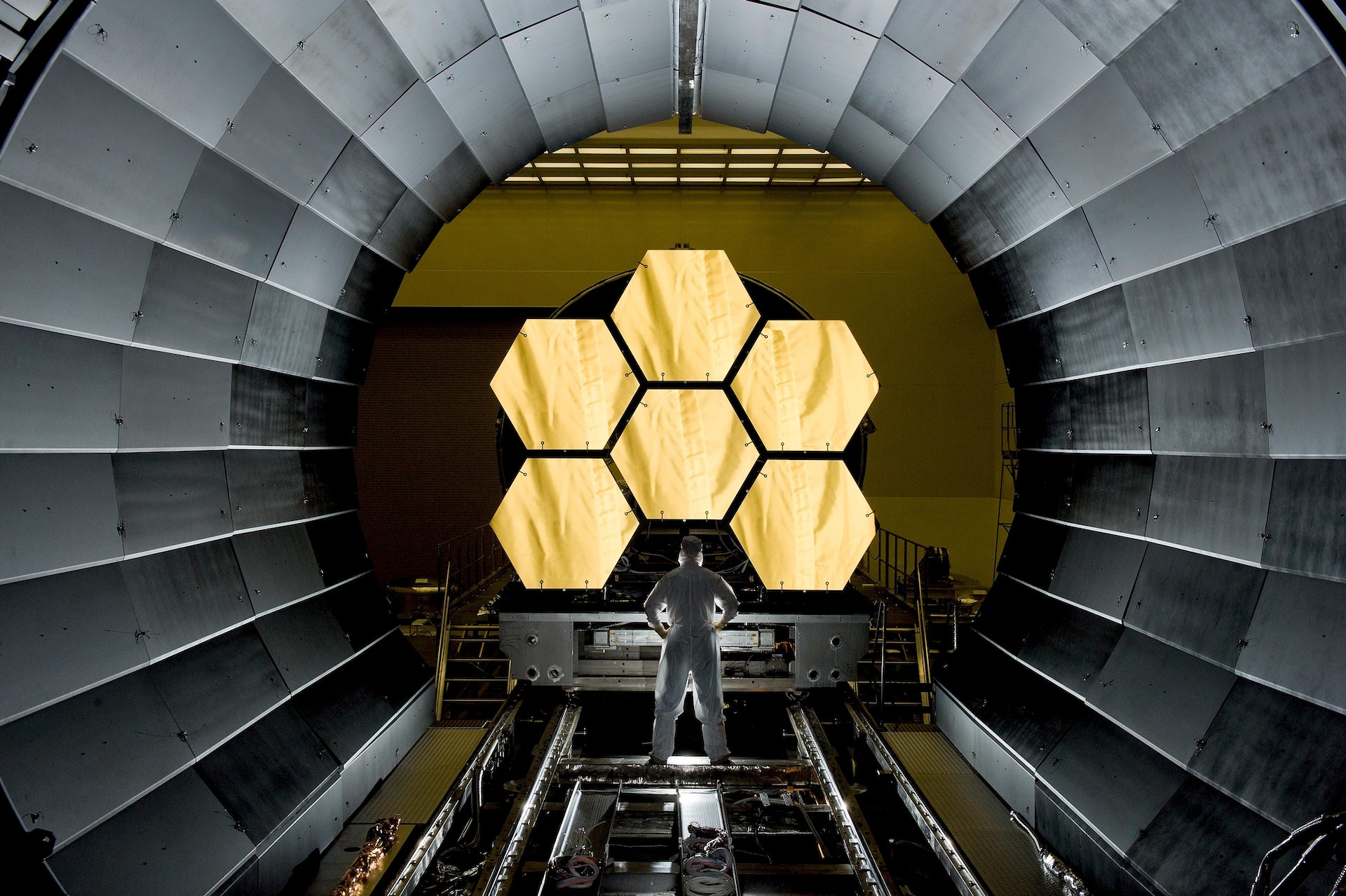 A person in a white jumpsuit standing in a science fiction setting.