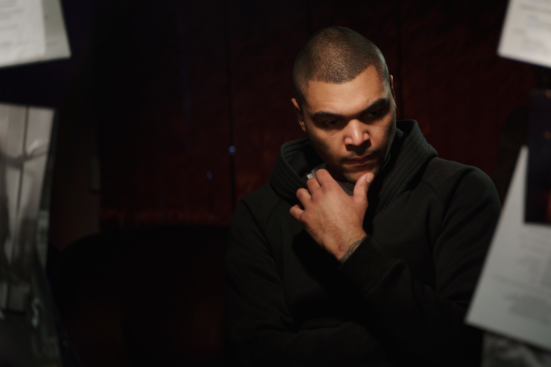 A person dressed in black sits in front of a mirror, appearing very concerned.
