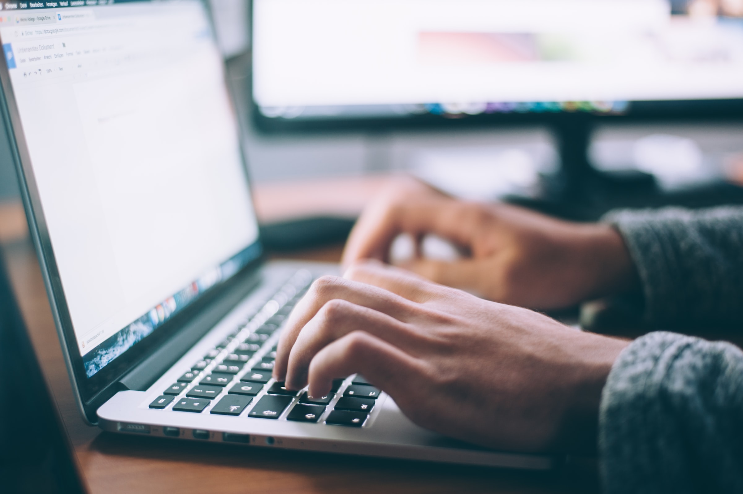 Hands type on the keyboard of a laptop.