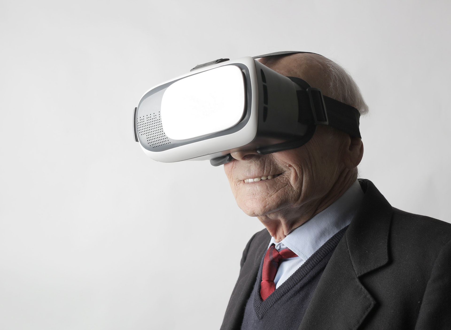 A smiling elderly person wears a virtual reality headset.