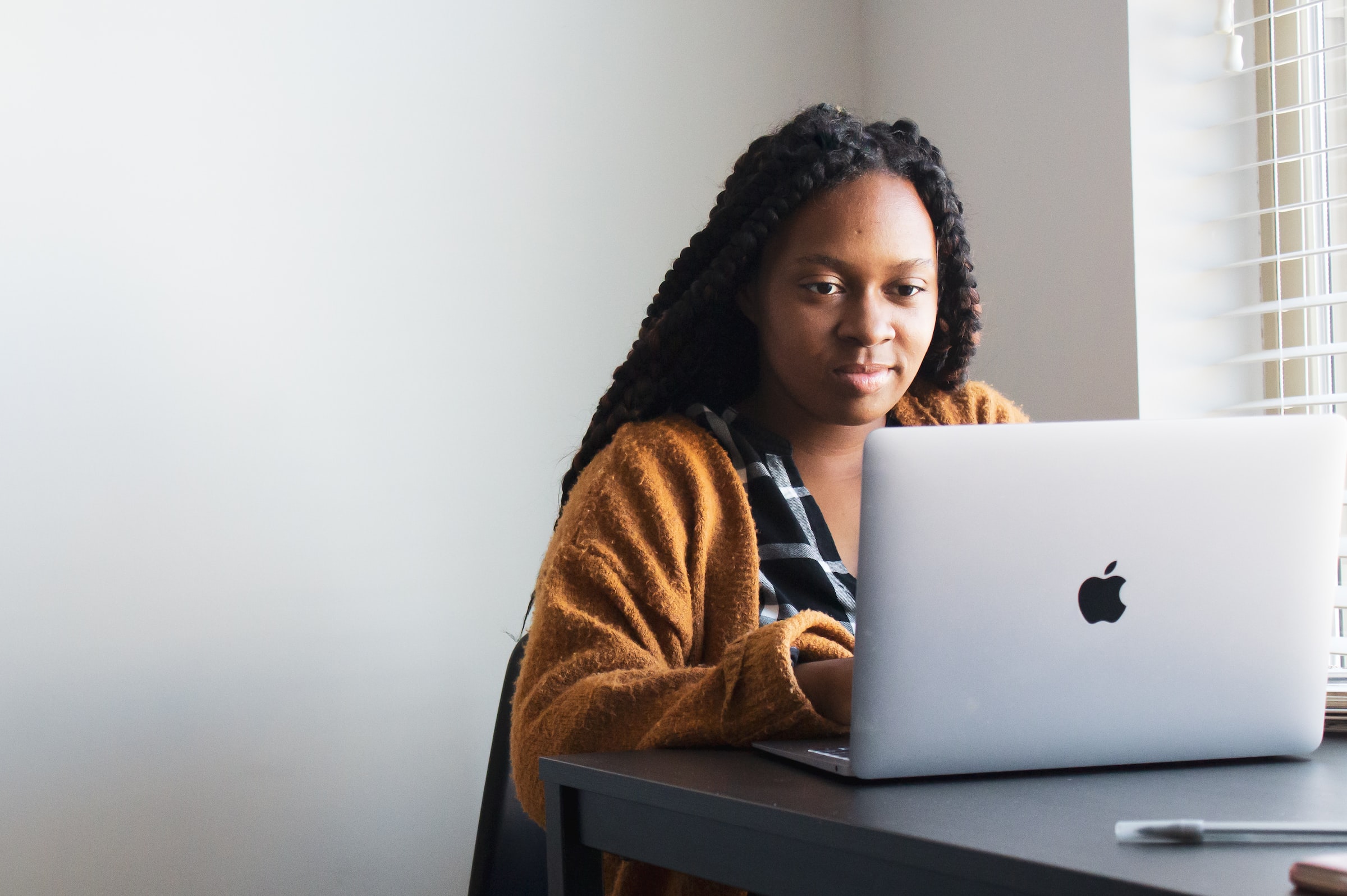 A person types on a laptop beside a window.