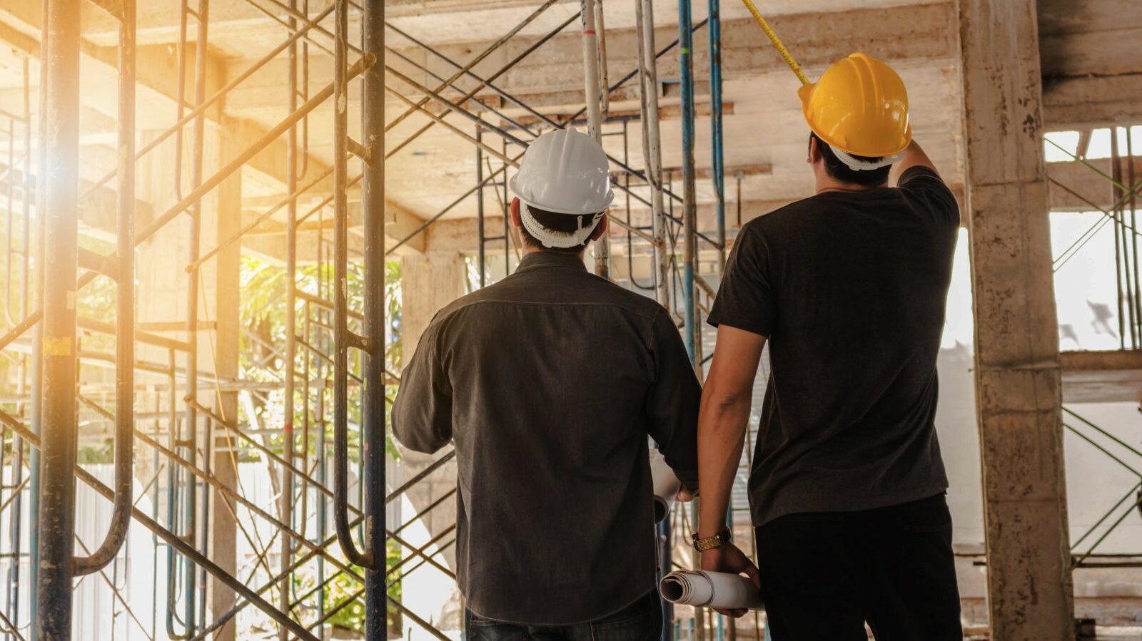 The picture of 2 construction workers discussing something on the building under construction