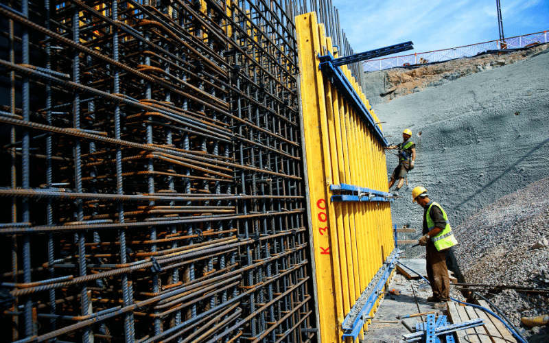 The picture of 2 construction workers working on the metal framework