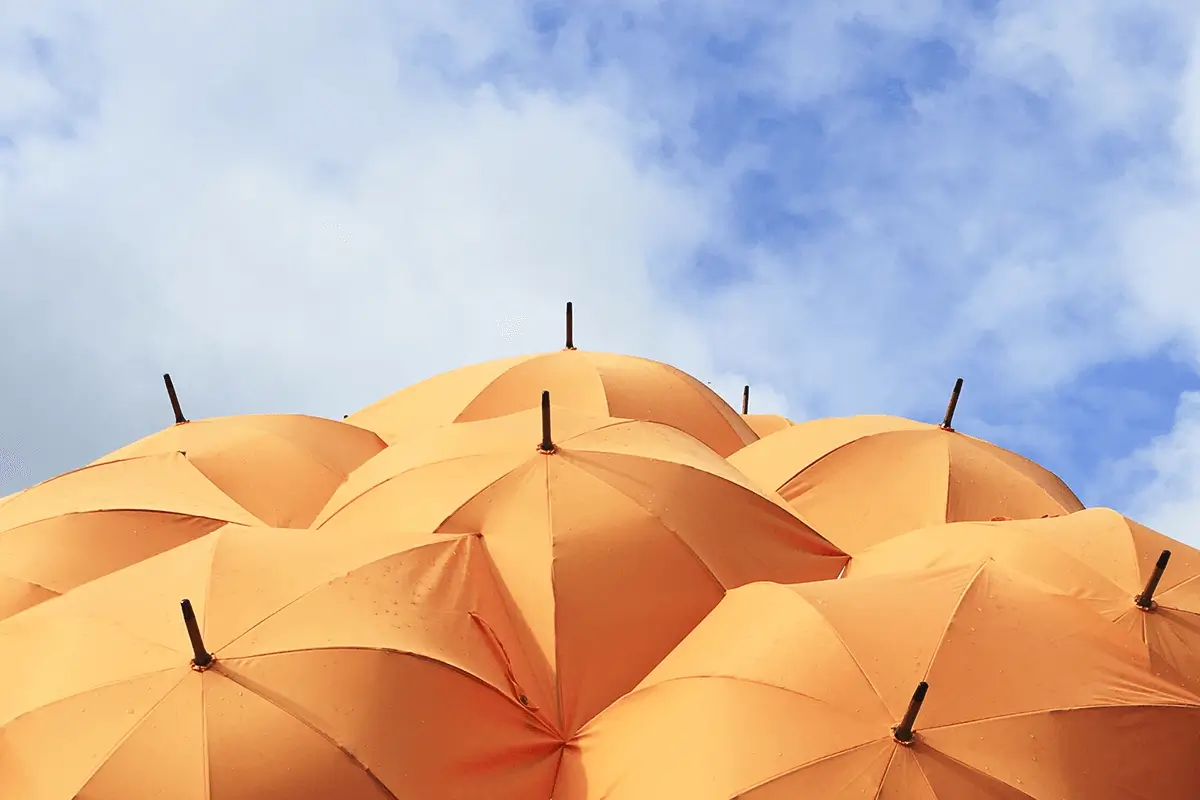 Multiple orange umbrellas floating in the sky.