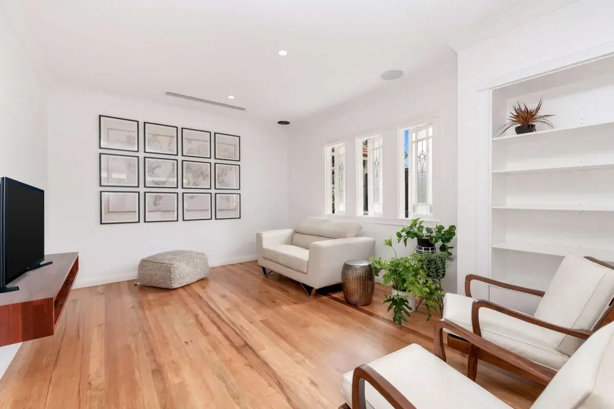 A living room with TV, sofa, and two chairs
