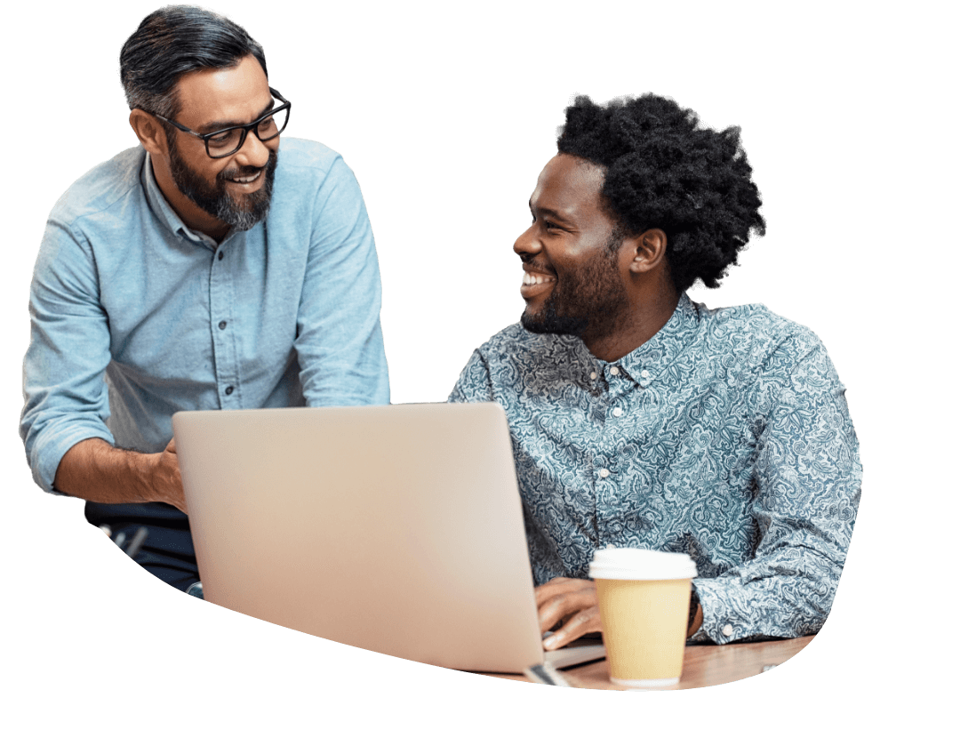 2 men smiling while sharing something on a laptop