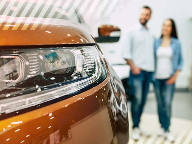 Happy couple viewing a used car at a dealership