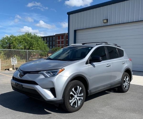 A sliver Toyota RAV4 parked next to a garage