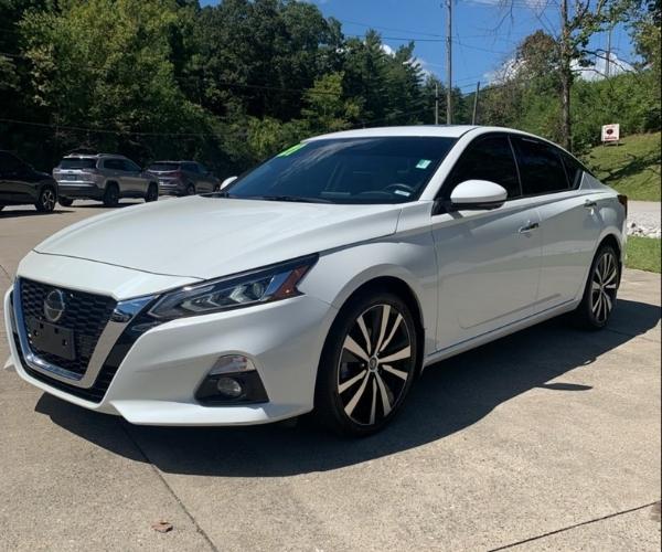 A white 2021 Nissan Altima in a empty suburban parking lot