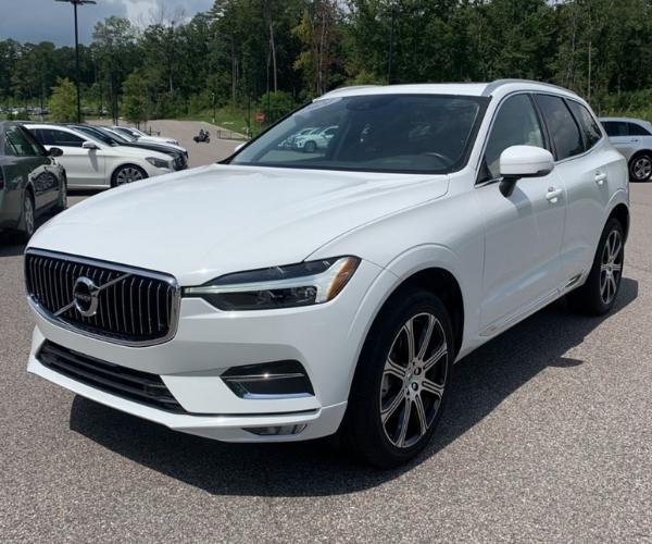 A white 2021 Volvo XC60 in a crowded dealers parking lot