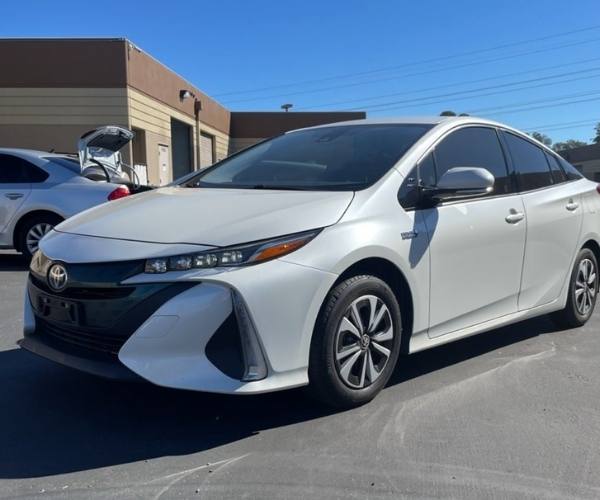 A white Toyota Prius in a busy dealer parking lot