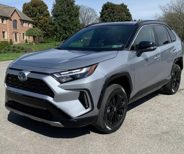 A silver Toyota RAV4 Hybrid in a neighborhood parking lot