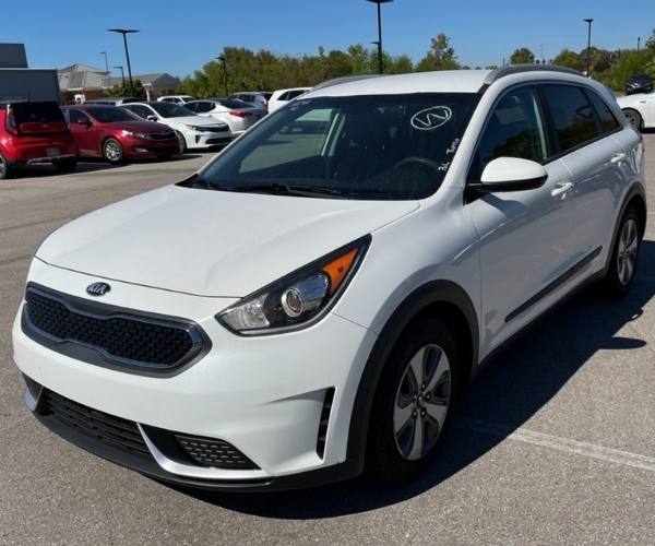 A white Kia Niro in a crowded dealer parking lot