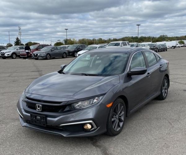 A grey Honda Civic in an empty dealer parking lot