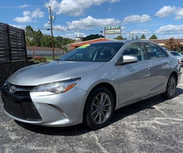 A silver Toyota Camry in a crowded dealer parking lot