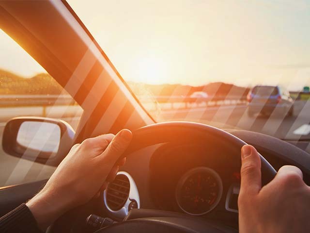A driver holds the steering wheel while driving a busy highway