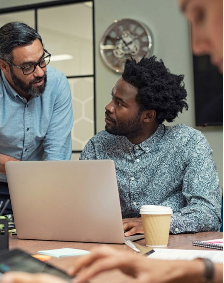 Image of two men talking with laptop open
