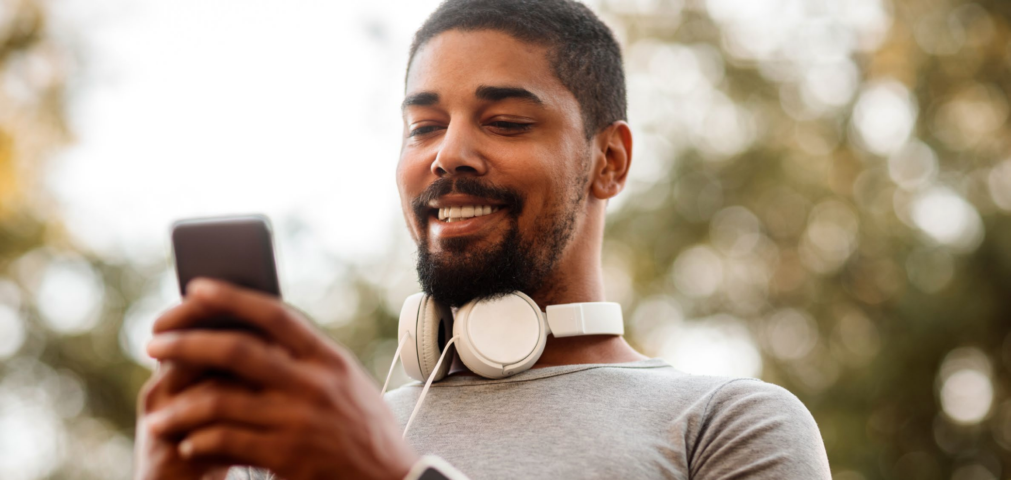 30-something man grinning and looking at his smartphone after exercise