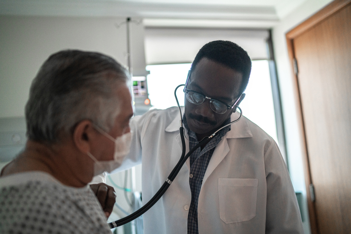 Doctor listening patient's heartbeat in hospital room