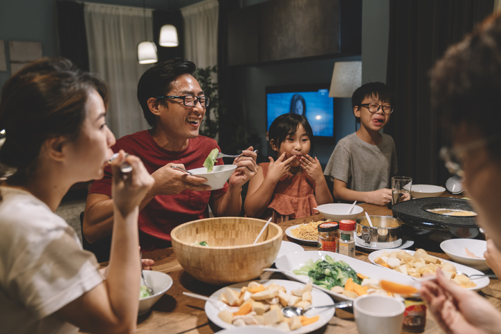 A family smiling and laughing around the dinner table.